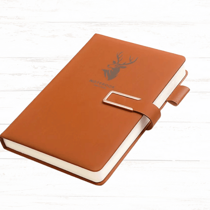 Brown notebook with a deer emblem on a white wooden surface