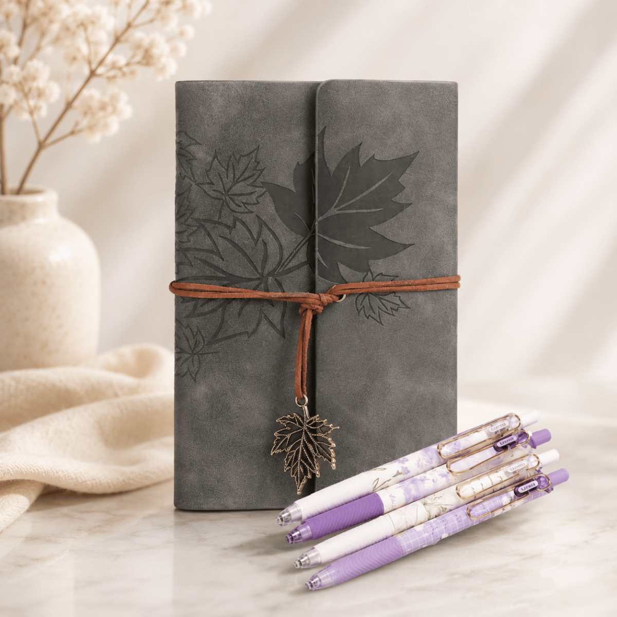 Grey faux leather leaf journal with lavender floral pens styled as a thoughtful stationery gift set on a soft neutral background.